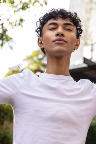 Young man practicing mindfulness outdoors in white t-shirt