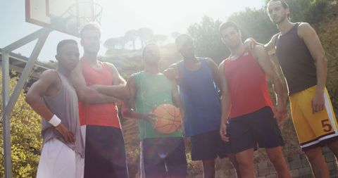 Diverse basketball team posing together in outdoor court