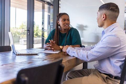 Two Professionals Discussing Plans in Modern Office with Laptop