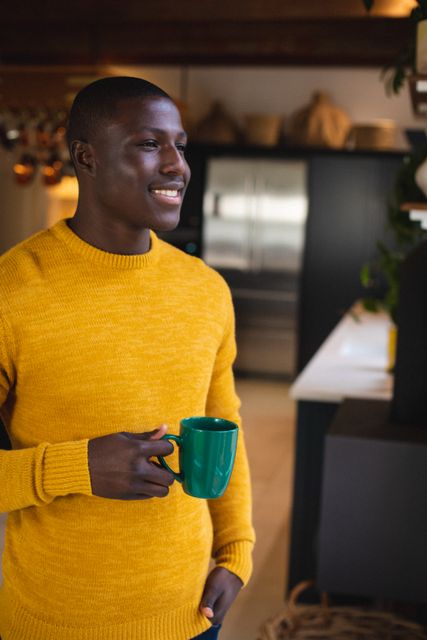 Thoughtful african american young man holding coffee cup looking away while standing at home - Download Free Stock Photos Pikwizard.com