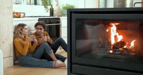 Cozy Couple Relaxing Near Fireplace with Mugs in Modern Kitchen