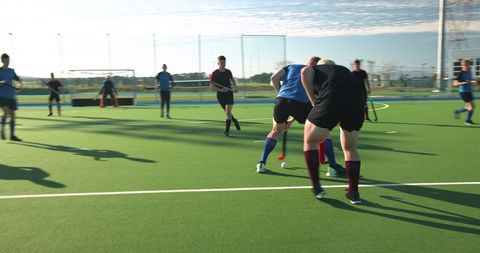 Male Athletes Playing Field Hockey on Sunny Day