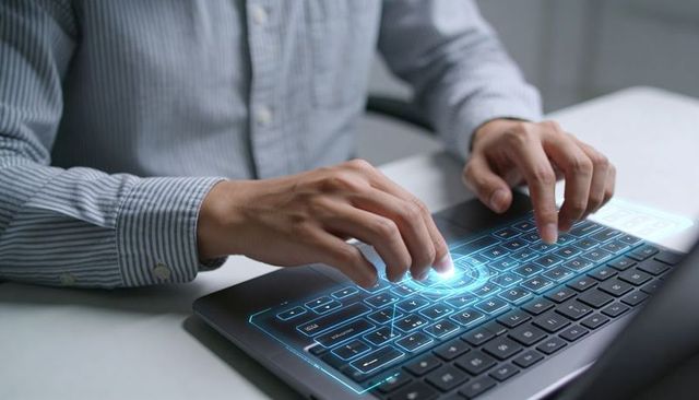 Man typing on laptop with holographic virtual keyboard projecting blue futuristic interface