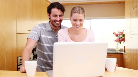 Smiling Couple Enjoying Laptop Experience in Modern Kitchen
