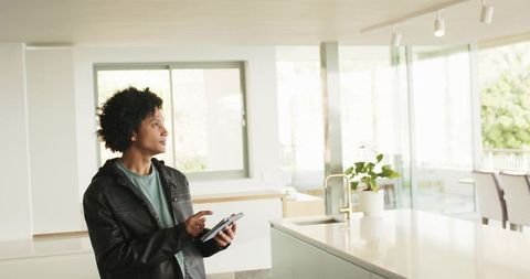 African American Inspecting Sunlit Modern Kitchen Island While Holding Tablet