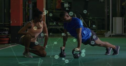 Trainer coaching client on push-ups with kettlebells