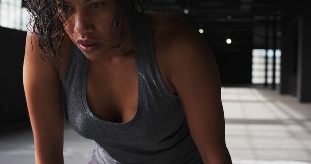 Close-up of a determined woman exercising in an industrial gym. Ideal for fitness advertisements or healthy lifestyle promotions, showcasing strength and dedication.