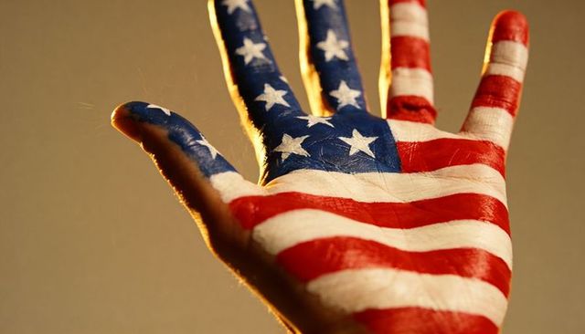 Right hand wearing american flag body paint showing stars stripes closeup warm lighting