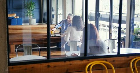 Senior Colleague Leading Informal Meeting with Two Friends in Modern Space