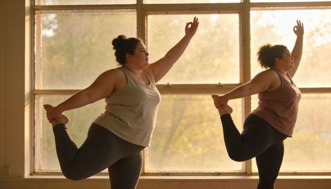 Plus size women practicing dancer pose in sunlit yoga studio embracing body positivity