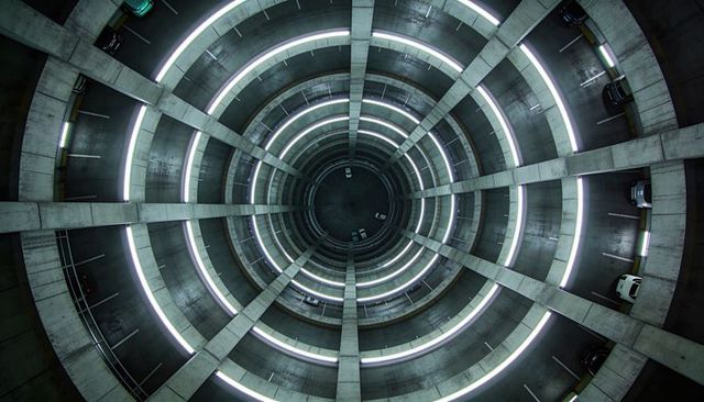 Spiraling circular parking ramp with led rings, concrete radial beams, urban symmetry