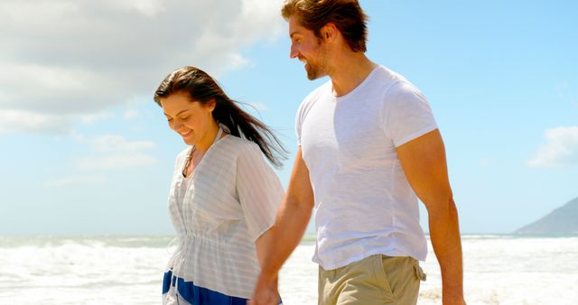 Happy caucasian couple holding hands and walking on beach. Relationship, togetherness, summer, leisure, vacation and lifestyle, unaltered.