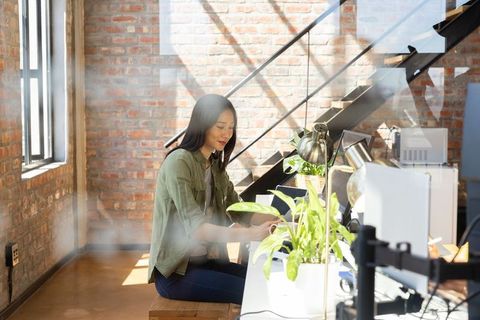 Asian Woman Working on Laptop in Modern Loft Office