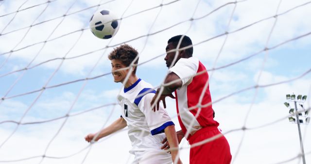 Competitive Football Match with Players Heading Ball Near Goal - Download Free Stock Images Pikwizard.com