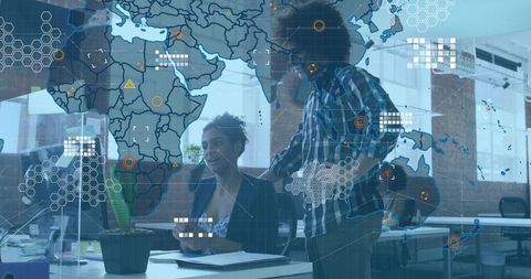 Two Colleagues Collaborating with Digital Data World Map in Office