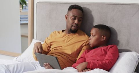 Father and Son Bonding Over Digital Tablet in Cozy Bedroom