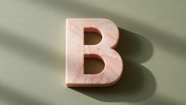3d marble letter b on sage green surface with soft shadows