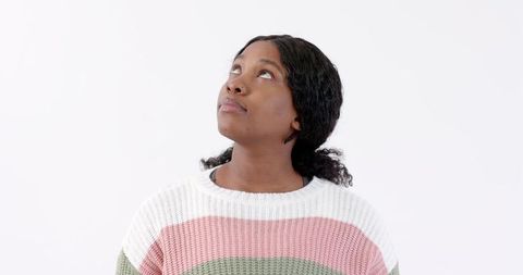 Pensive Woman in Striped Sweater Gazing Upward Indoors