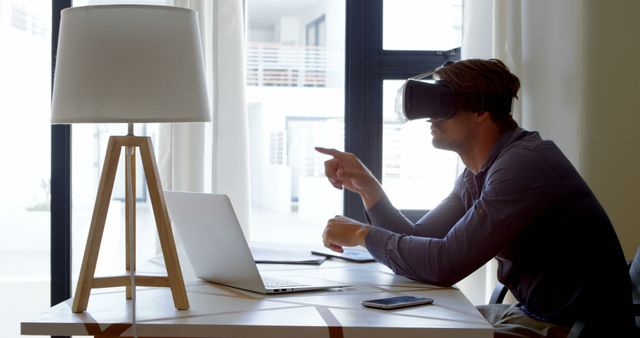 Man using virtual reality headset while working at desk - Download Free Stock Images Pikwizard.com