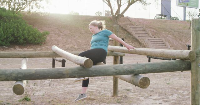 Woman participating in an outdoor obstacle course, showing determination and hard work. Ideal for content focusing on fitness, wellness, health regimes, outdoor activities, and motivational themes. Can be used for blogs, fitness programs, promotional materials for exercise regimes, or inspirational content on physical perseverance and goal setting.