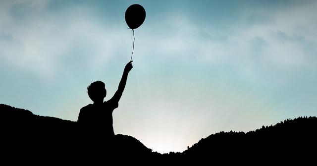 Digital composite of Silhouette boy holding balloon against sky during sunset