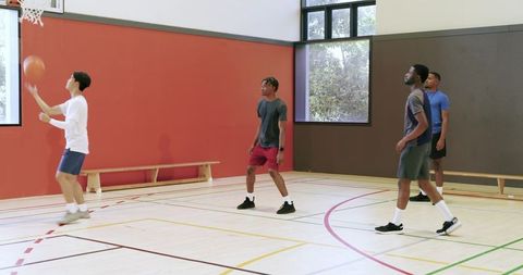 Friends playing basketball indoors practicing passing shooting teamwork camaraderie on gym court