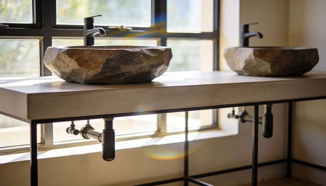 Handcrafted stone vessel sink on concrete vanity with matte black faucets