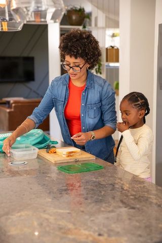Mother and daughter preparing sandwich together in bright kitchen