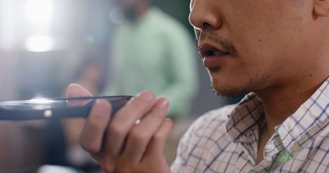 Man using voice command on smartphone in office environment