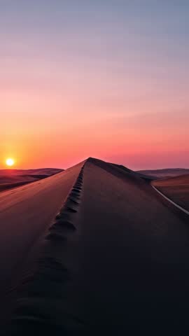 Tracking along dune crest at sunset golden hour vertical desert ridge with footprints