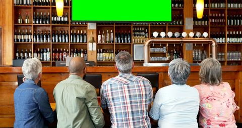 Middle-Aged Group Watching TV with Green Chroma Key at Bar