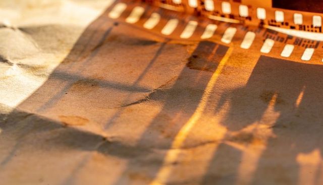 Casting 35mm film strip shadows on crumpled kraft paper warm vintage golden light