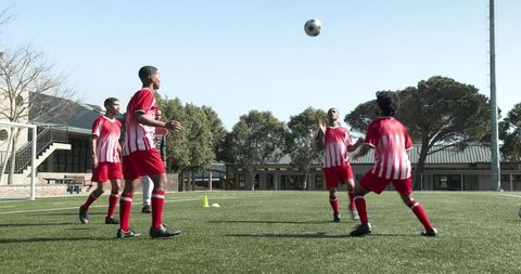 Teen soccer players practicing on field with coach guidance