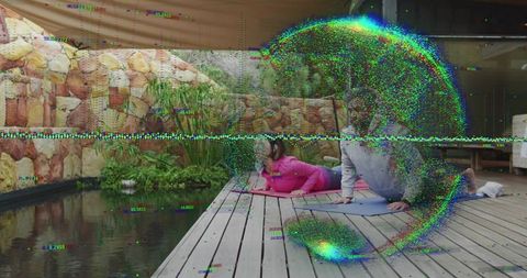 Couple practicing partner yoga on garden deck beside pond, morning fitness routine