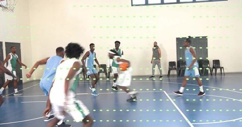 Basketball players dribbling and defending on blue indoor court while coach watching