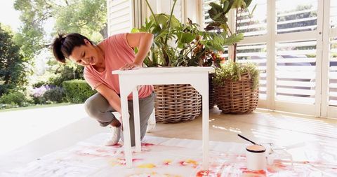 Woman refreshing furniture painting table in sunny room