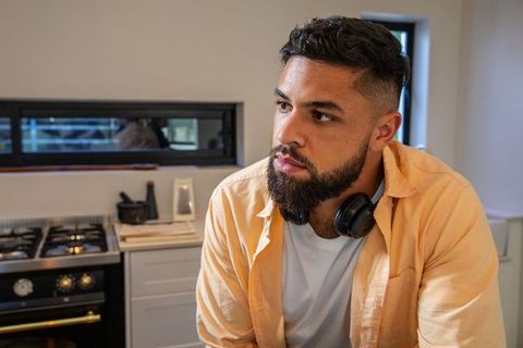 Casual Man Dreaming in Modern Kitchen with Headphones