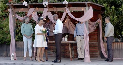 Diverse Senior Couple Exchanging Vows in Outdoor Celebration