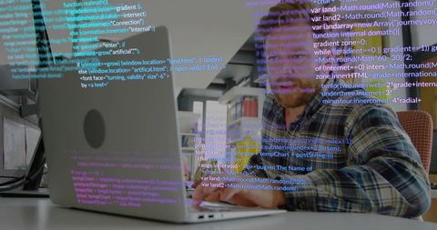 Mid-adult man typing code on silver laptop with code overlay in modern office workspace