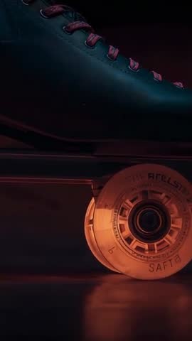 Vertical close-up of retro quad roller skate wheel glowing amber during studio pan
