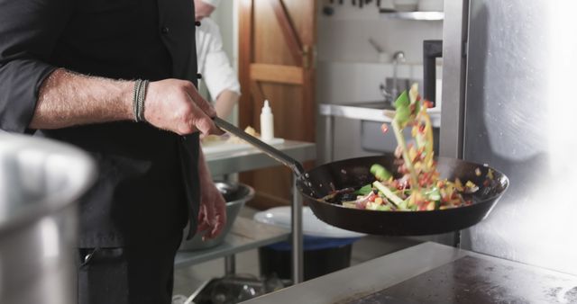 Chef flipping vegetables in hot frying pan in kitchen - Download Free Stock Images Pikwizard.com