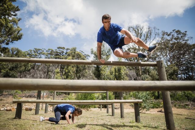 Man and woman participating in an outdoor obstacle course, showcasing teamwork and physical fitness. Ideal for use in fitness blogs, training programs, sports advertisements, and motivational content.