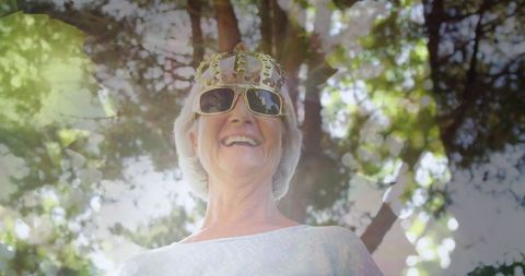 Joyful Senior Woman Wearing Crown Outdoors Beneath Trees