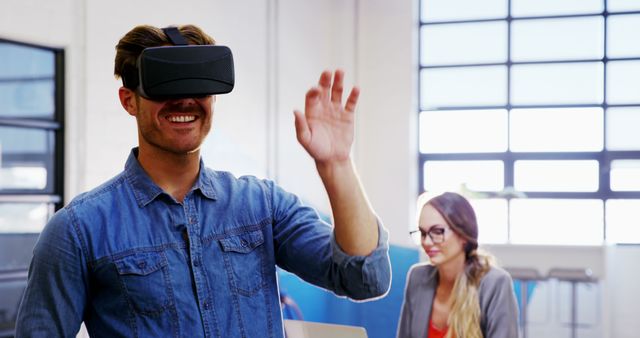 Man Using VR Headset in Modern Office with Colleague in Background - Download Free Stock Images Pikwizard.com