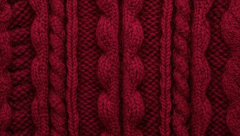 Burgundy cable-knit fabric close-up showing thick yarn texture for cozy knitwear
