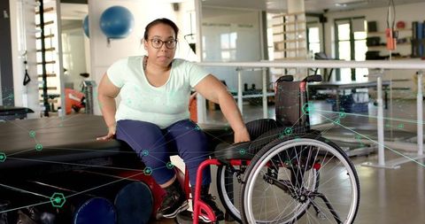 Woman transferring from padded bench to wheelchair during physical rehabilitation session