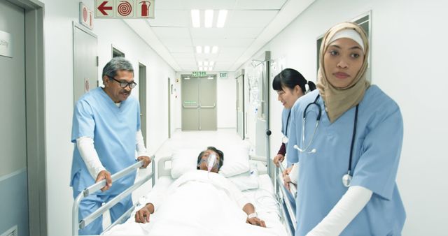 Diverse medical team in a hospital corridor, with copy space. Senior Biracial man and Young Asian woman transport a patient, assisted by a Biracial woman.