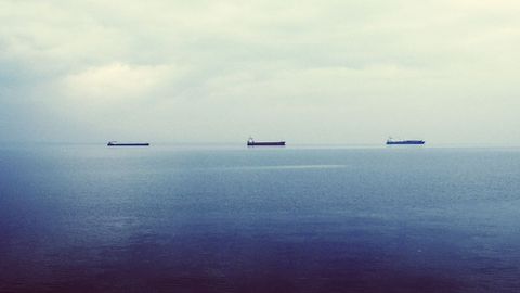 Tranquil ocean view with distant cargo ships