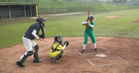 Female Baseball Player Preparing to Bat on Sunny Field