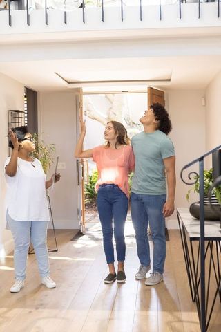 Diverse couple touring modern sunlit entryway with african american agent leading tour